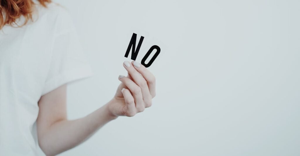 ¿Qué ocurre cuando un adolescente siente que no encaja en ningún grupo? Close-up of person holding the word 'NO' in black letters on a white background, conveying a message of refusal.