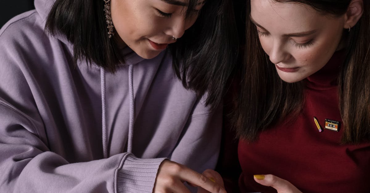 Two teenage girls looking at a smartphone screen together indoors.