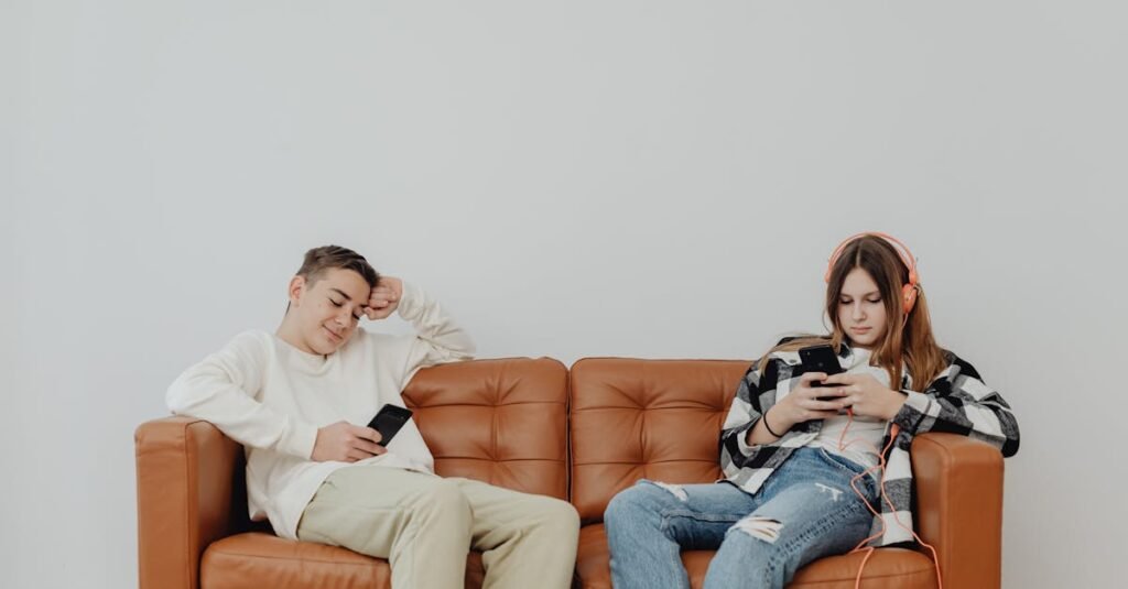 ¿Cómo afectan las redes sociales a la autoestima de los adolescentes? Teenagers lounging on a leather sofa using smartphones, displaying modern leisure.