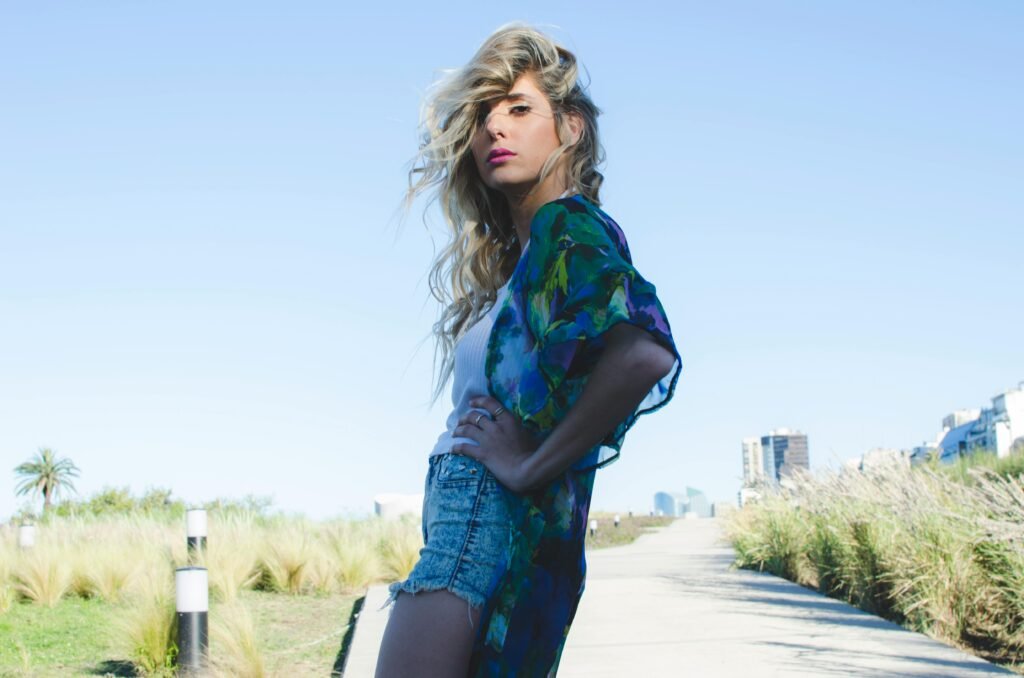 Fashionable young woman poses confidently on an urban pathway, showcasing casual summer style.