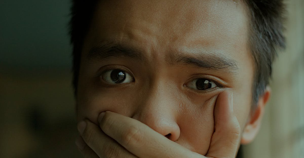 A young man with a distressed expression, covering his mouth.