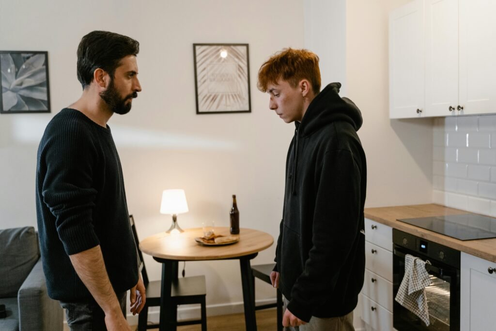 Two men having a serious conversation in a modern kitchen setting.