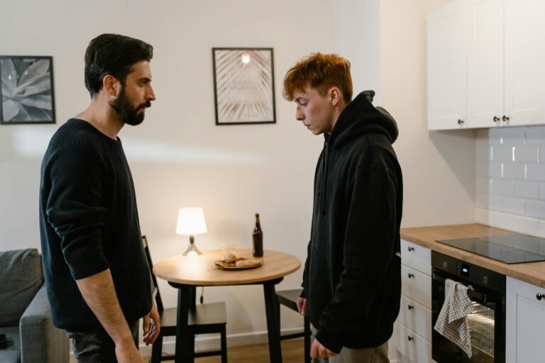 Two men having a serious conversation in a modern kitchen setting.