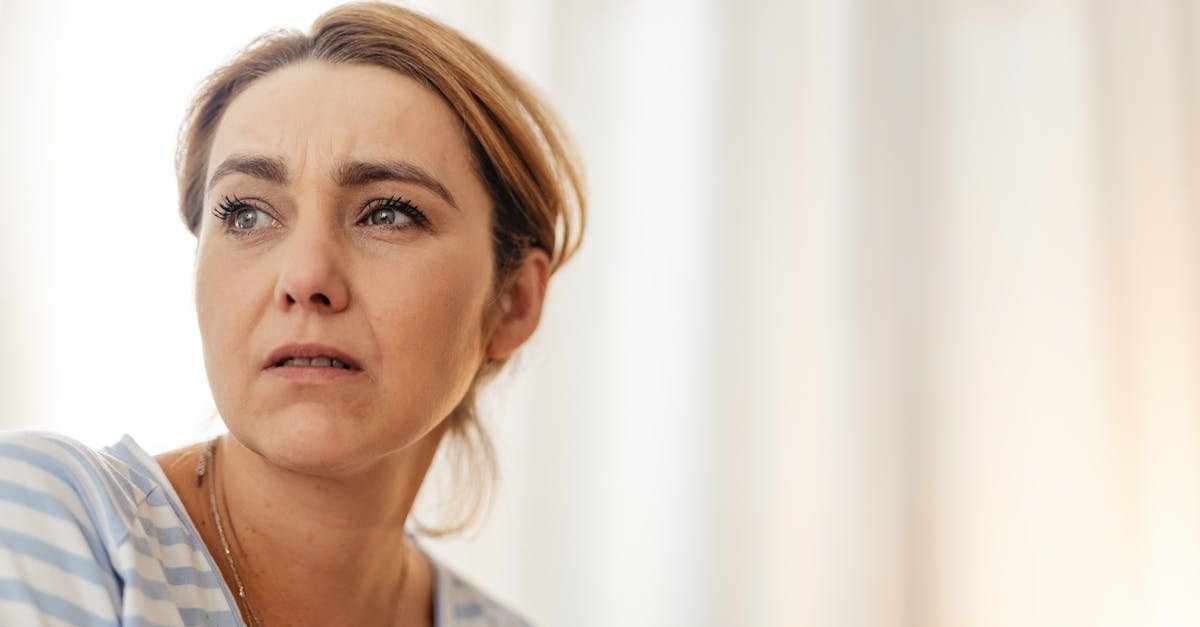 Thoughtful woman in striped shirt gazing away in gentle indoor lighting.